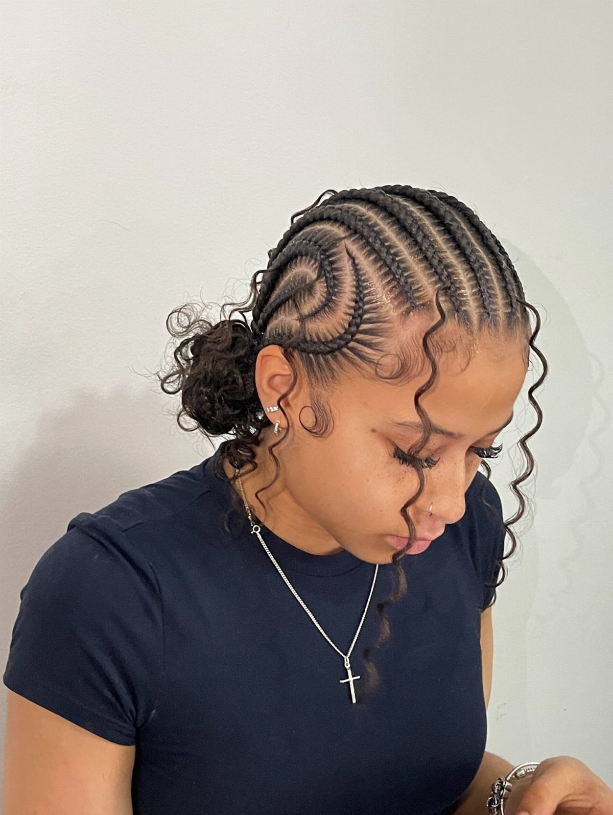 Cornrowed hairstyle with loose curls gathered at the back and tendrils framing the face