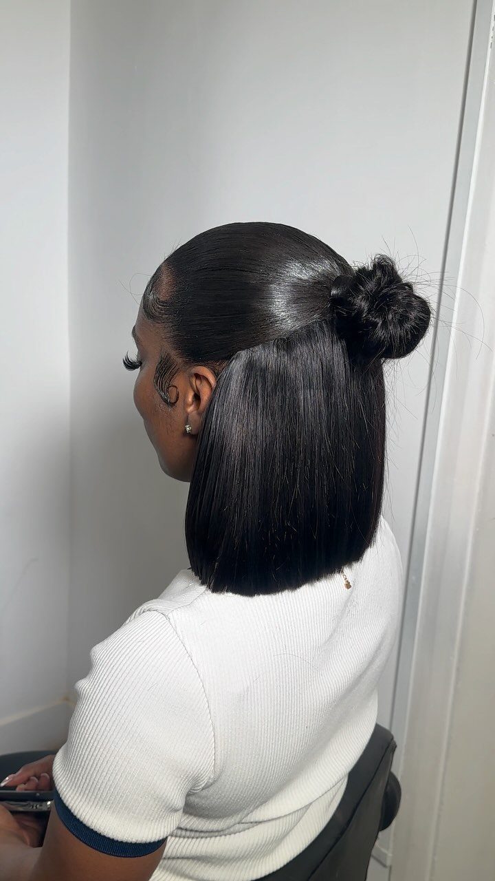 Half-up bun gathers the upper section of straight shoulder-length black hair