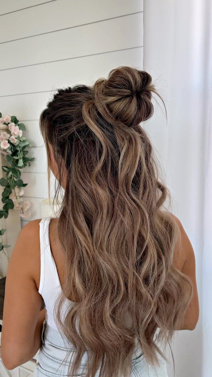 Long wavy brown hair styled in a half-up top knot