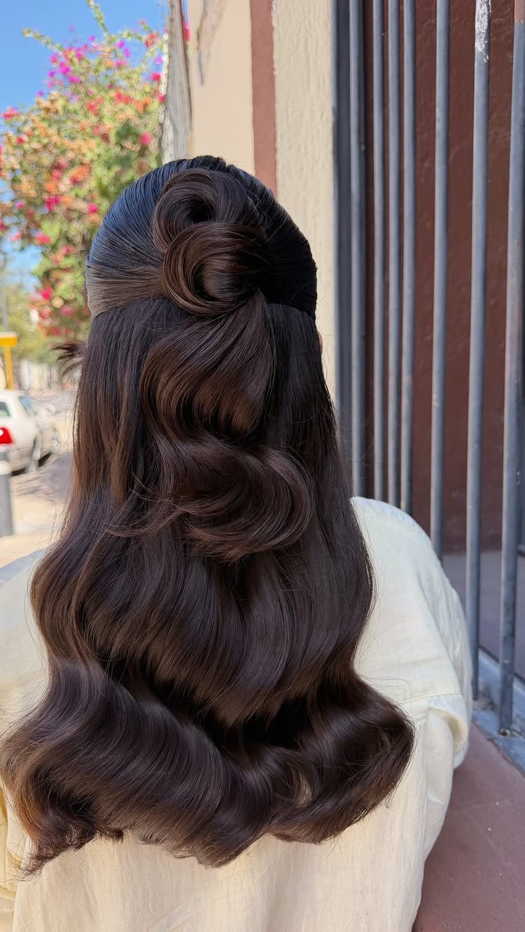 Long dark hair in a twisted half-up style with sleek, uniform Hollywood waves