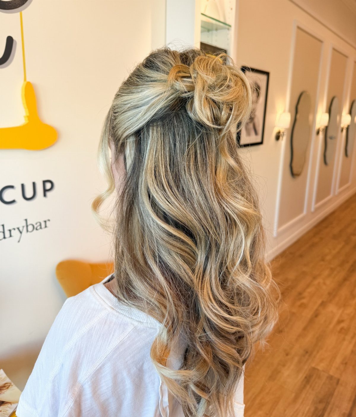 Long blonde waves gathered loosely at the back in a relaxed half-up style