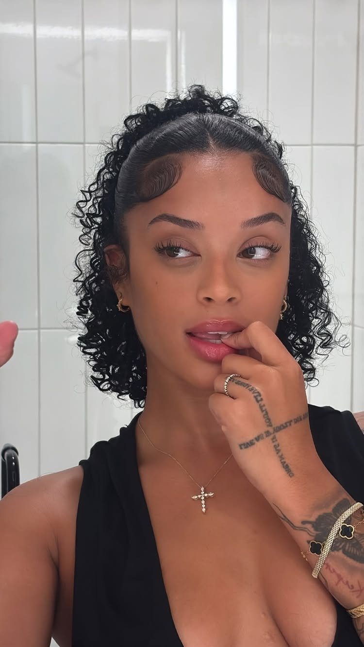 Woman wearing natural curls half up with the remaining curls loose