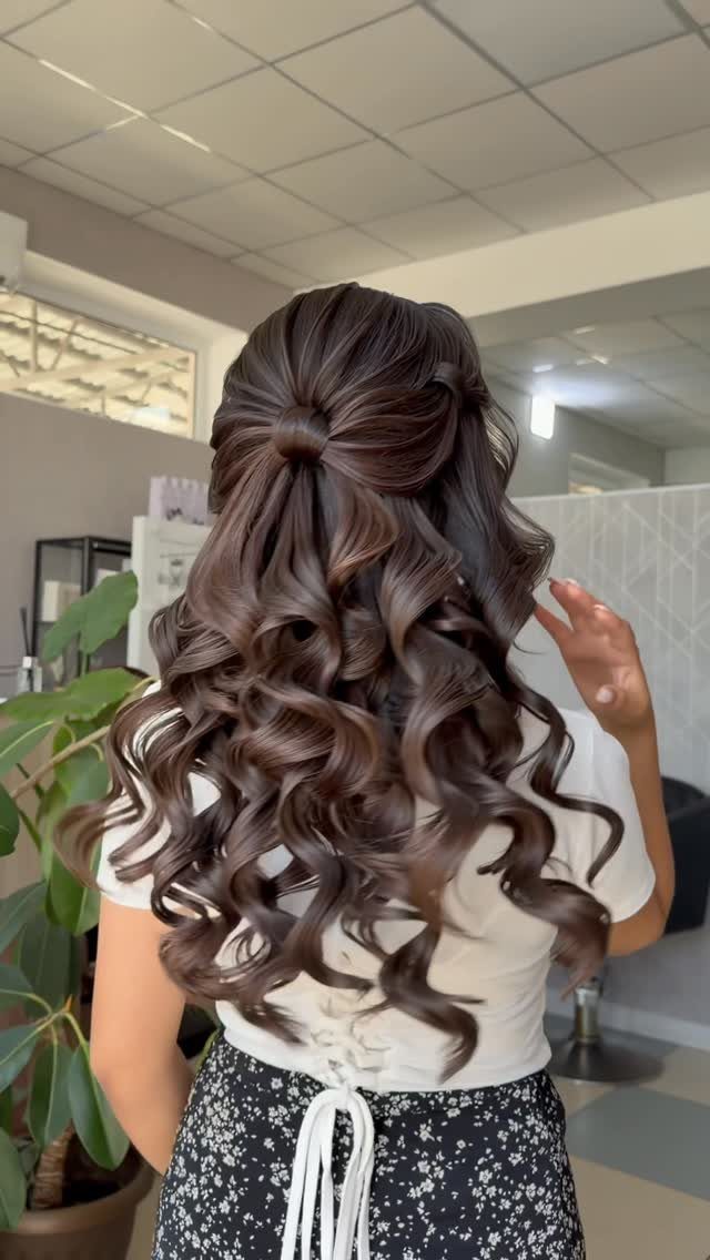 Brown hair arranged in a self-made half-up bow above loose curls