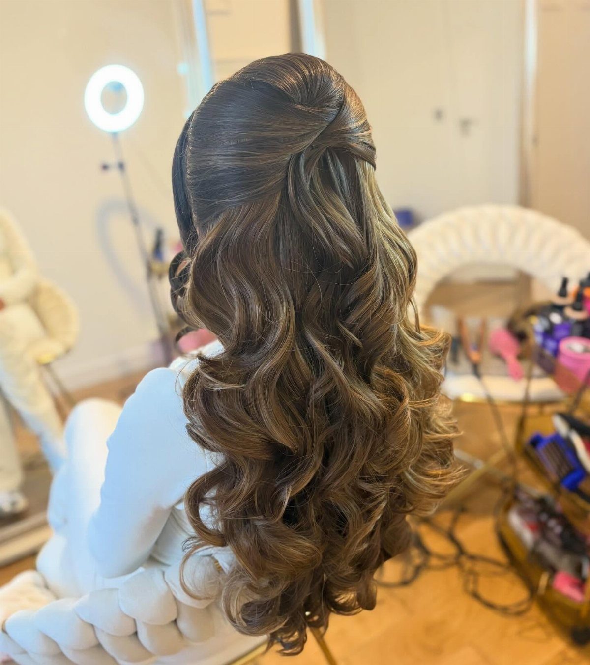 Teased brown half-up hairstyle with long, cascading curls in a salon