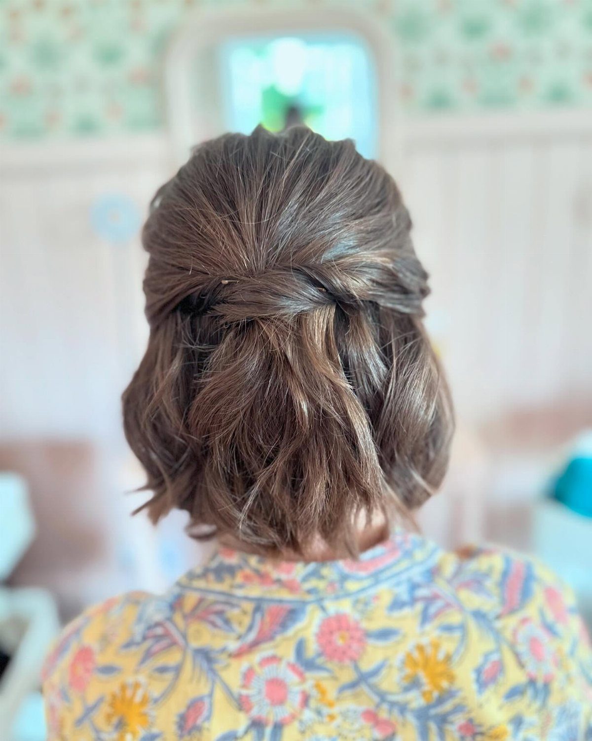 Short brown bob gathered into a simple twisted half-up hairstyle