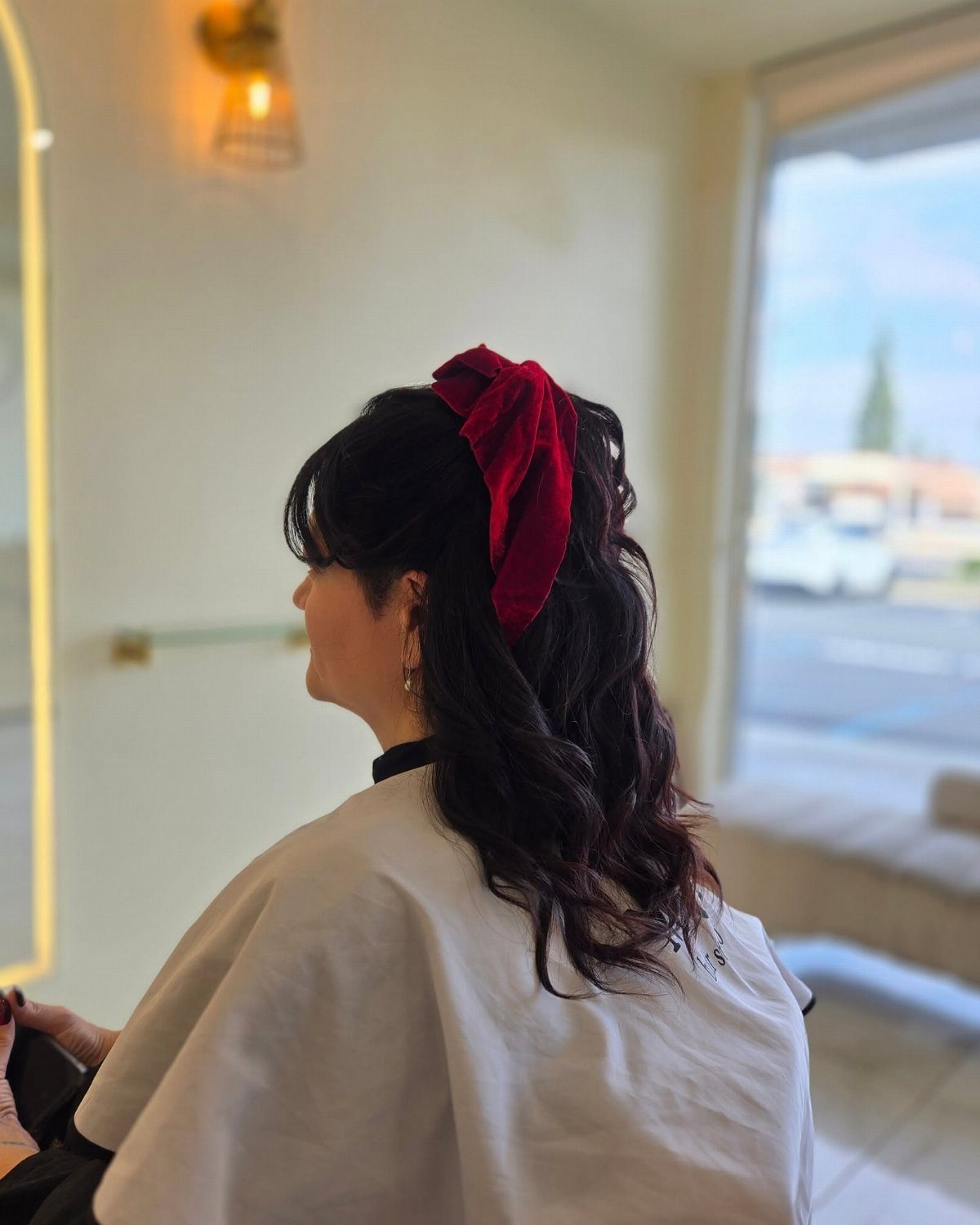 Dark soft waves held half up with a large red fabric bow clip