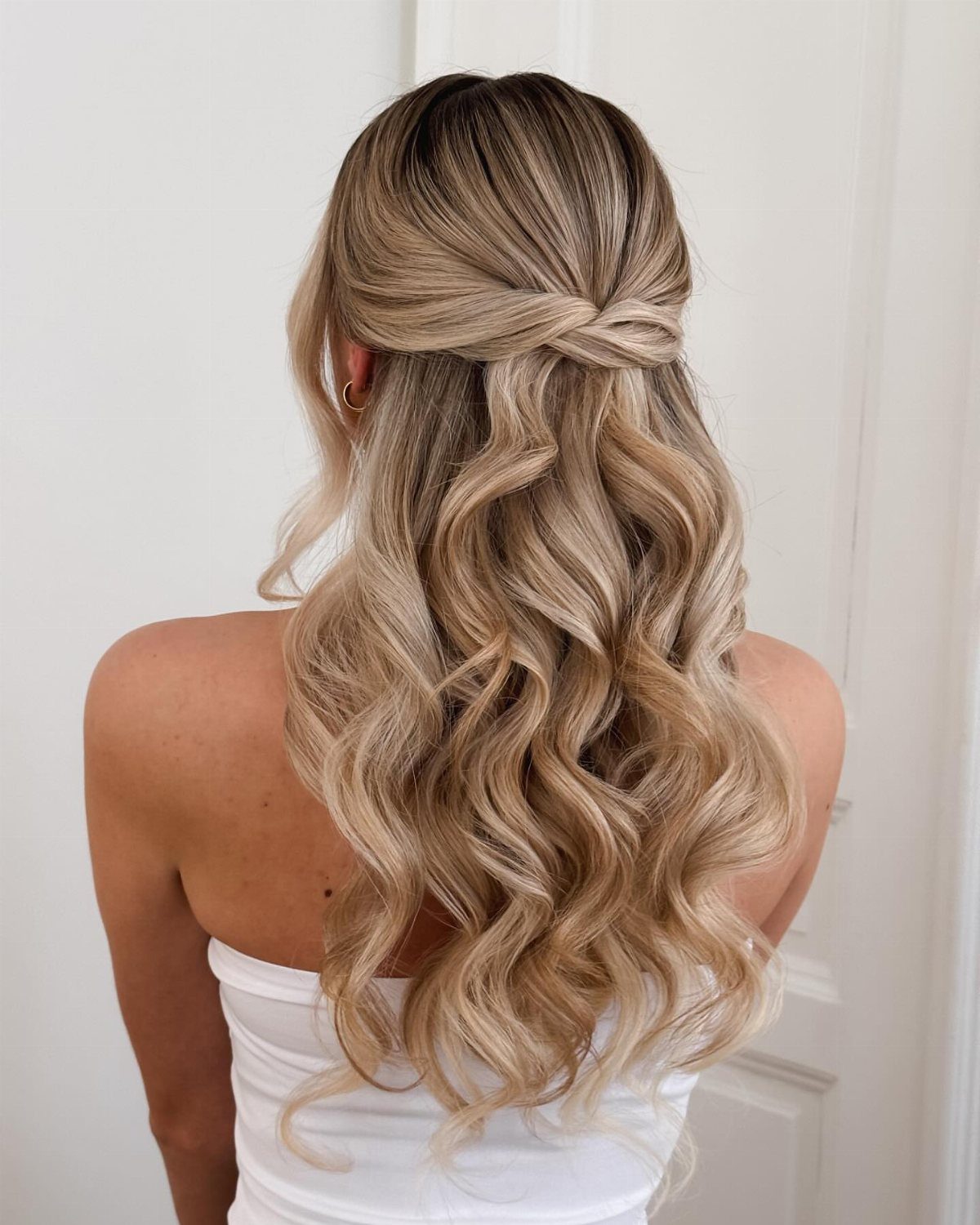 Blonde half-up hairstyle with crossed twists and long defined waves