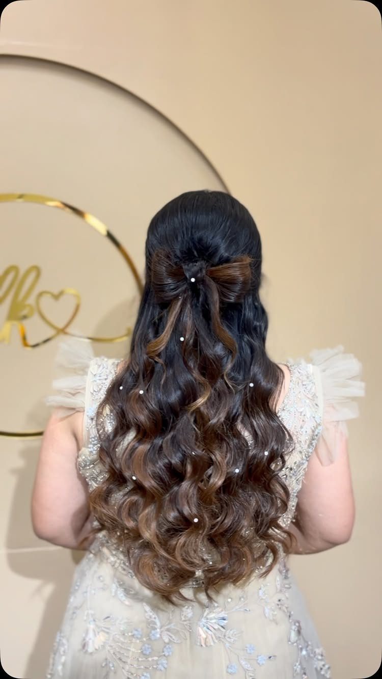 Long wavy half-up hair adorned with a pearl-accented bow