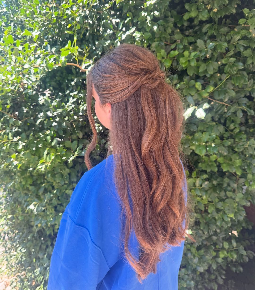 Long auburn hair arranged in a simple half-up twist with loose waves