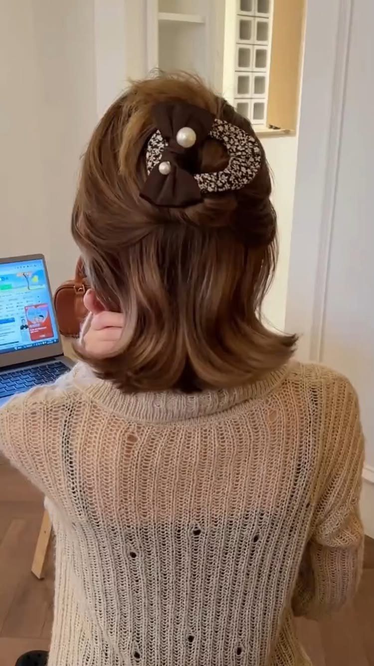 Brown half-up hairstyle with soft waves and a pearl-accented decorative clip