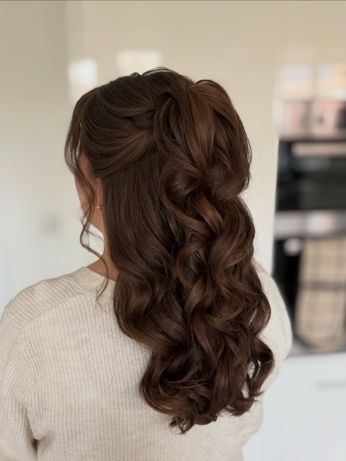 Dark curly half-up hairstyle twisted at the crown, with loose curls cascading down