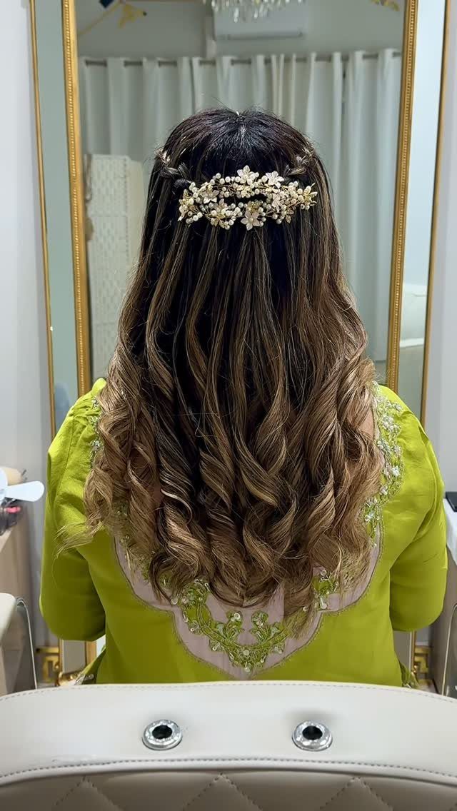 Long curled hair with soft twists secured by a pearl floral hairpiece