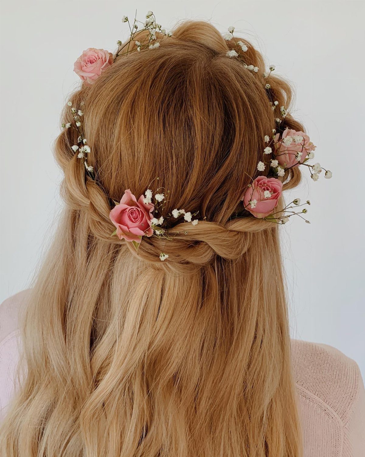 Blonde half-up hairstyle decorated with pink roses and tiny white flowers
