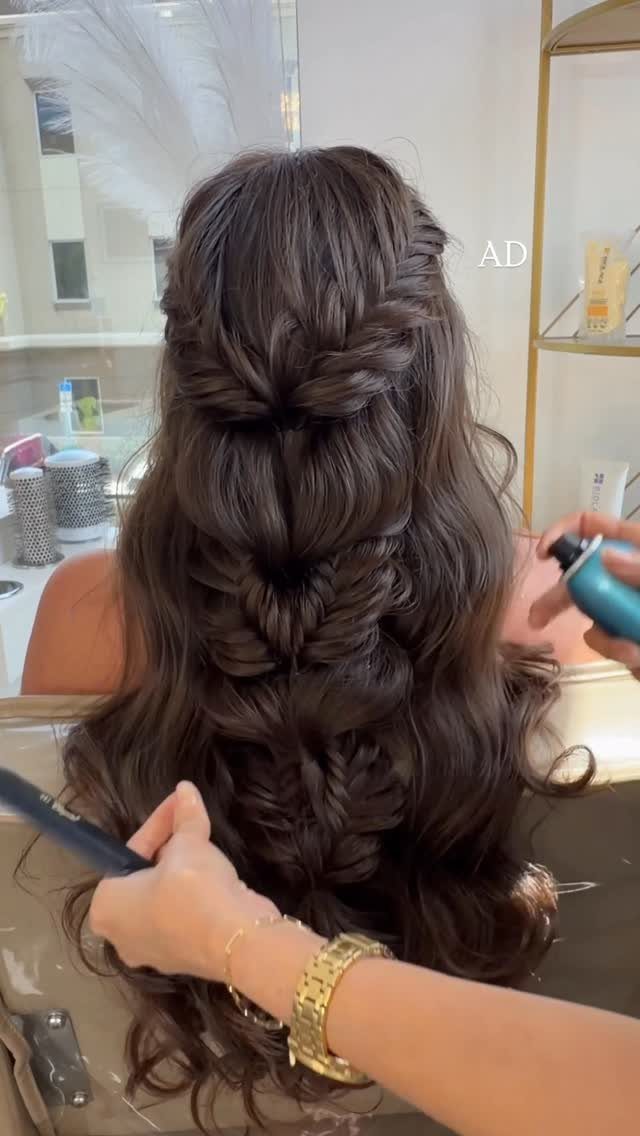 Long dark curls arranged in loose twists and braids by a stylist