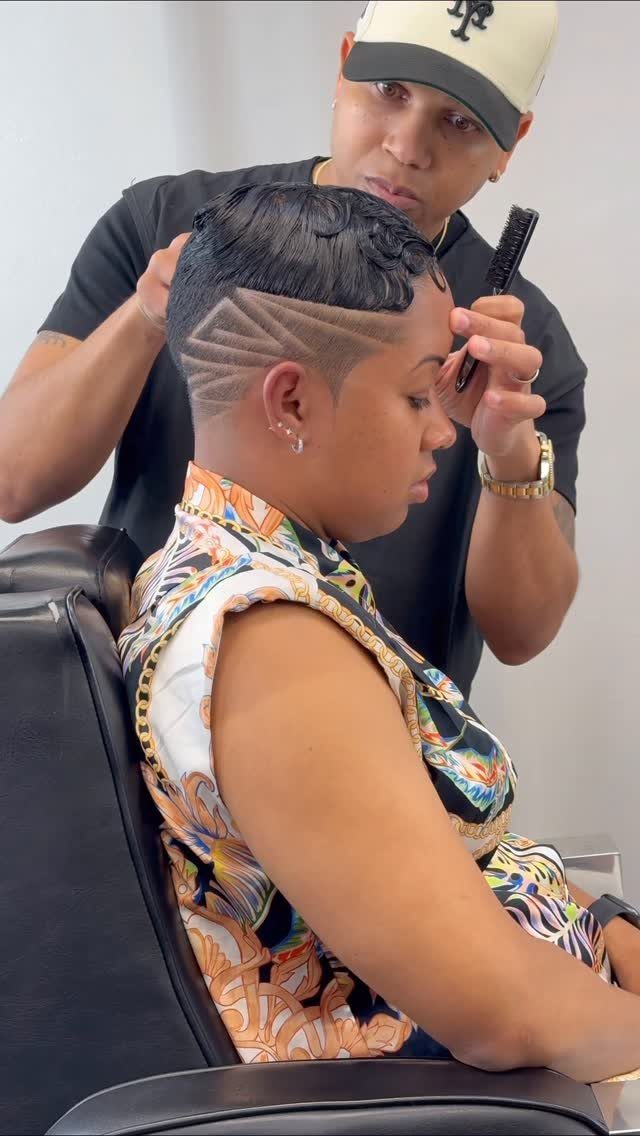 Client receives a short haircut with shaved geometric lines and longer hair on top