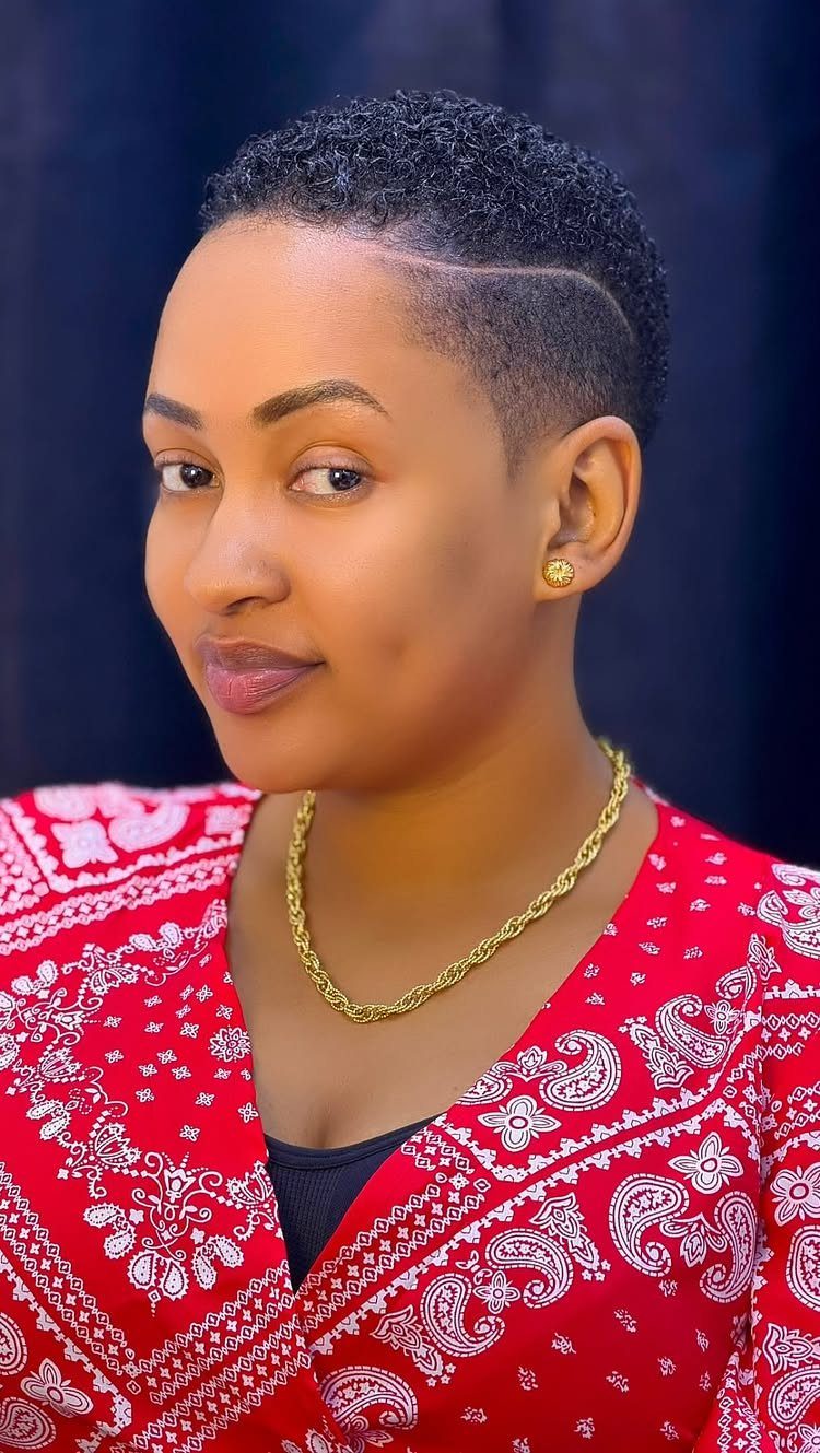 Short curly taper haircut with faded sides and a curved shaved design