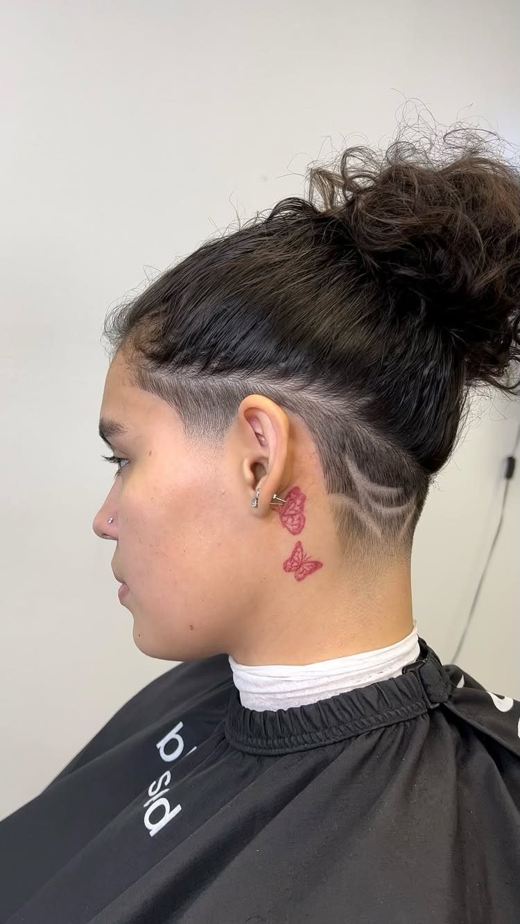 Shaved part line defining a dark undercut haircut beneath a tied bun