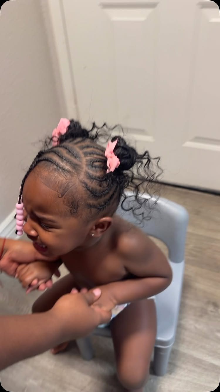 Child with cornrow braids gathered into small buns with pink bows