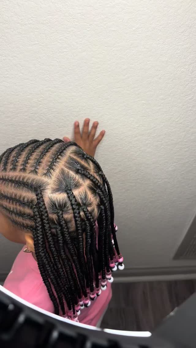 Child showing intricate cornrow braids with geometric partings and pink-and-white beads