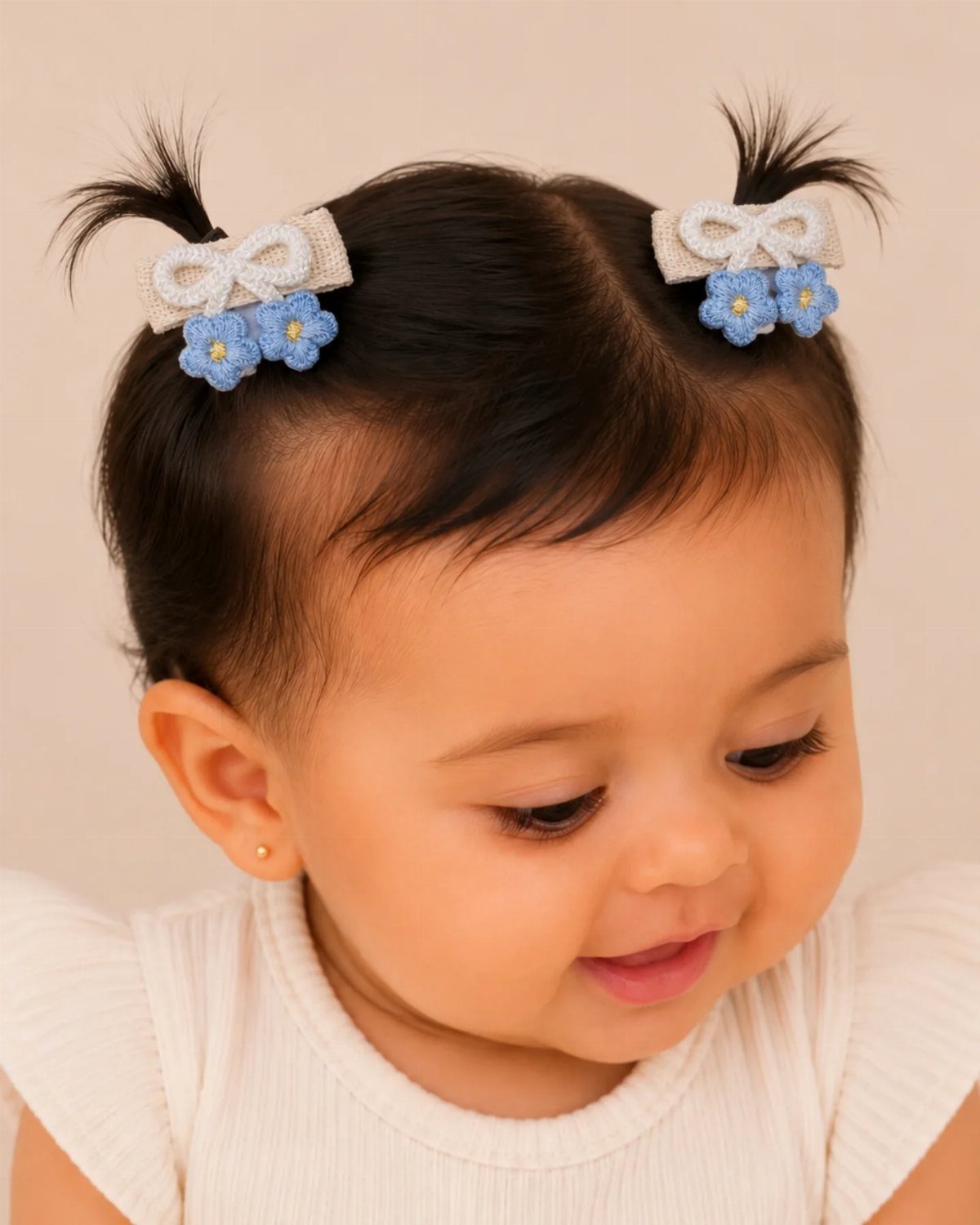 Baby with short side-parted hair and white bows with blue flower clips