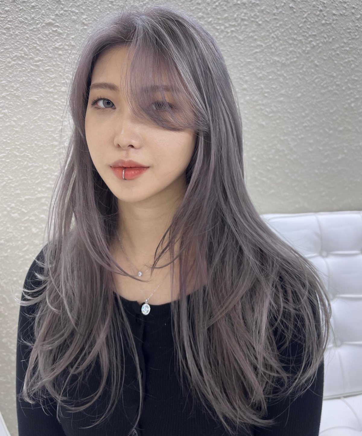 Woman with long, layered ash-gray hair and wispy bangs