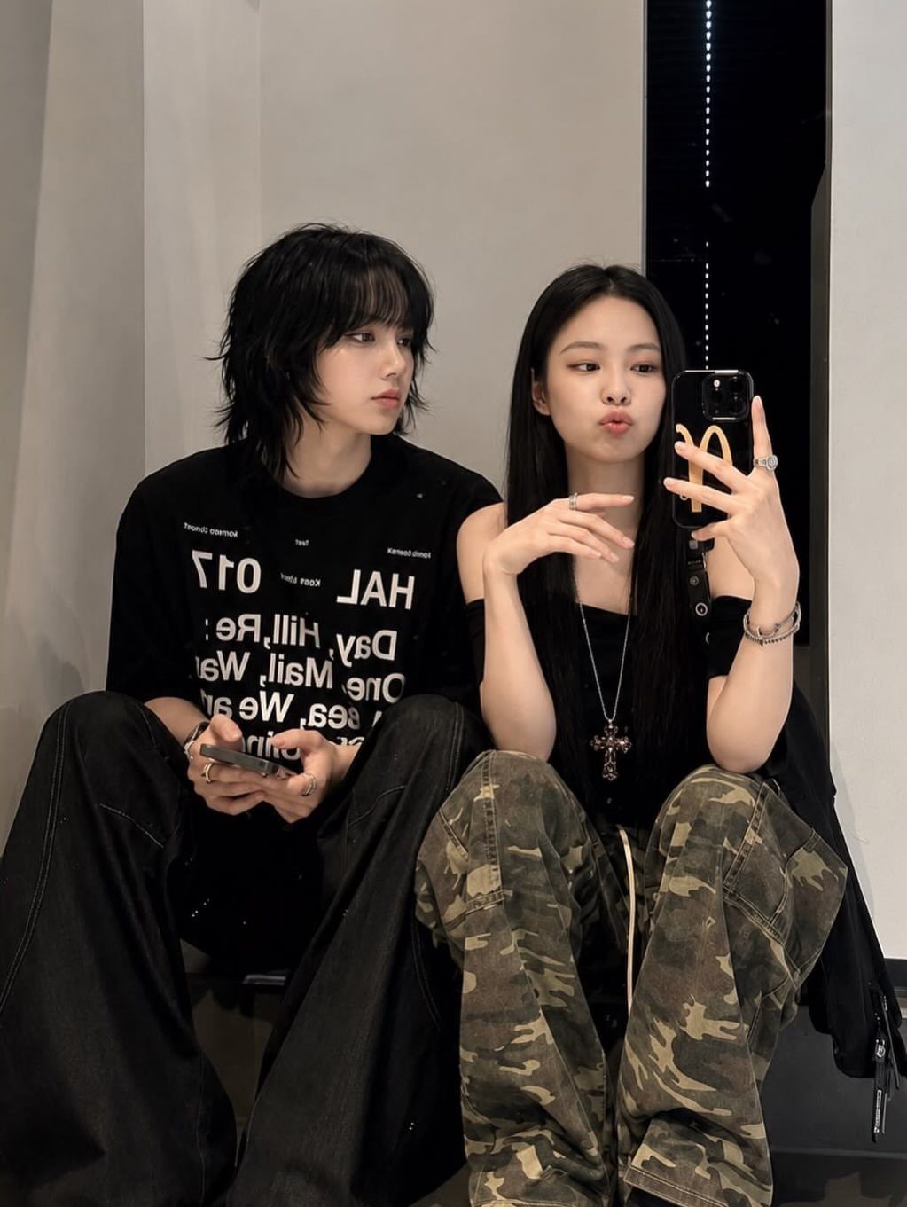 Person with shaggy black layered hair and feathered ends sits beside a friend