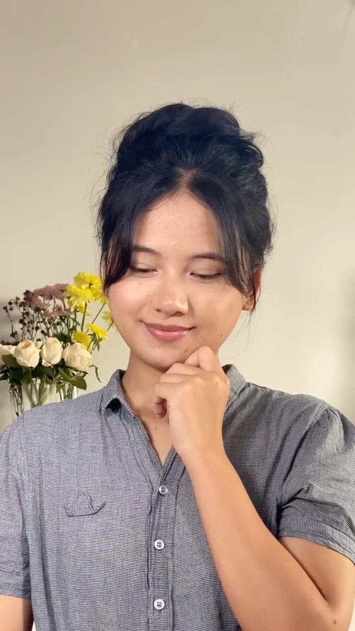 Woman with dark hair in a loosely gathered, tousled high bun