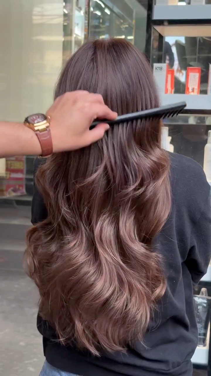 Long brunette hair with lighter brown ends is combed into glossy waves