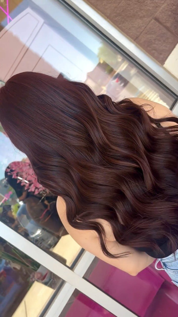Long brunette hair with copper and auburn tones styled in glossy waves