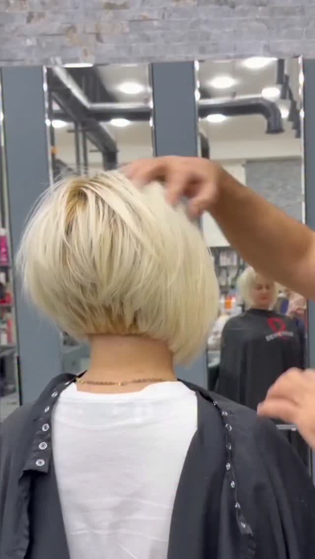 Short blonde graduated bob with a tapered nape in a salon