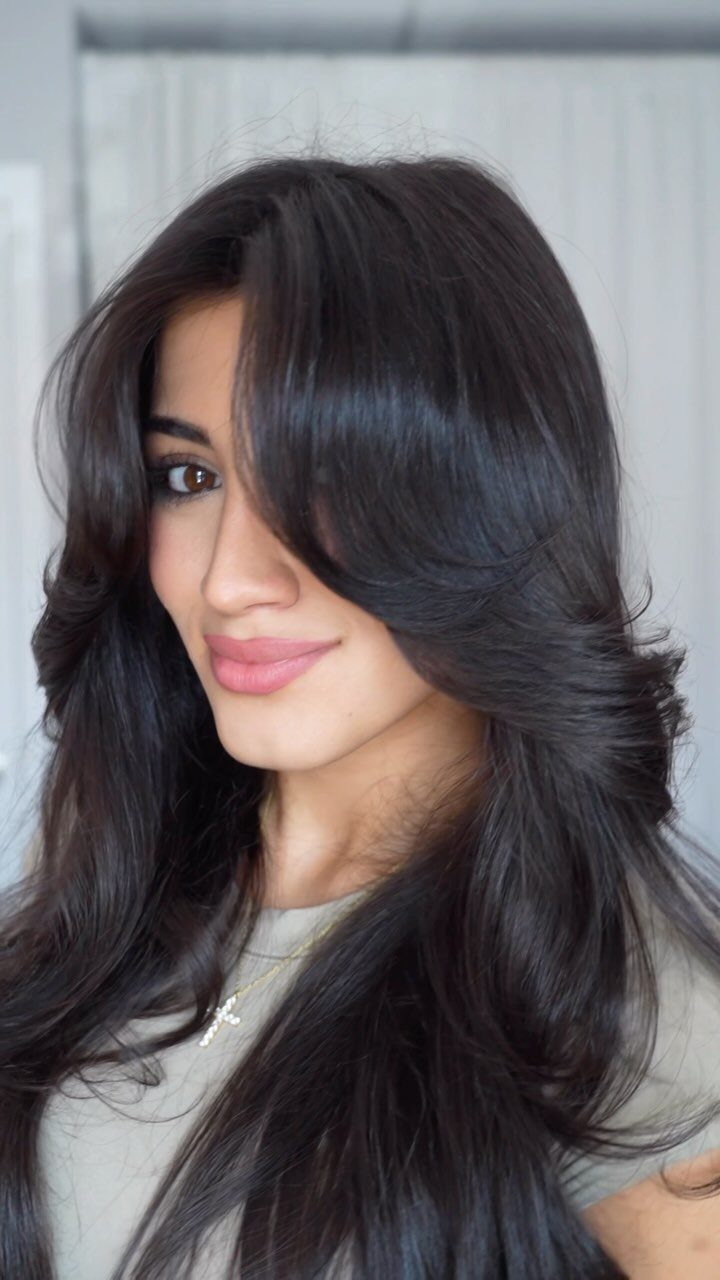 Woman showing long dark layered hair with a sweeping side fringe