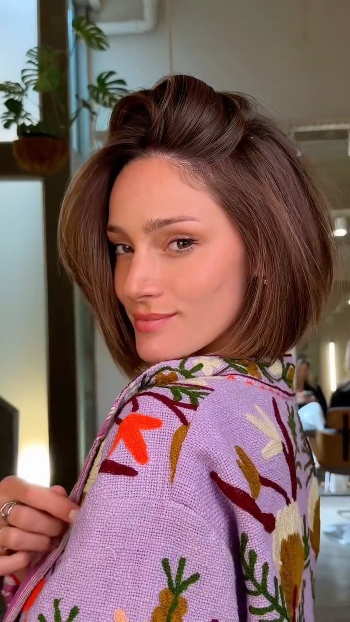 Woman showing a chin-length brunette bob with a lifted side part