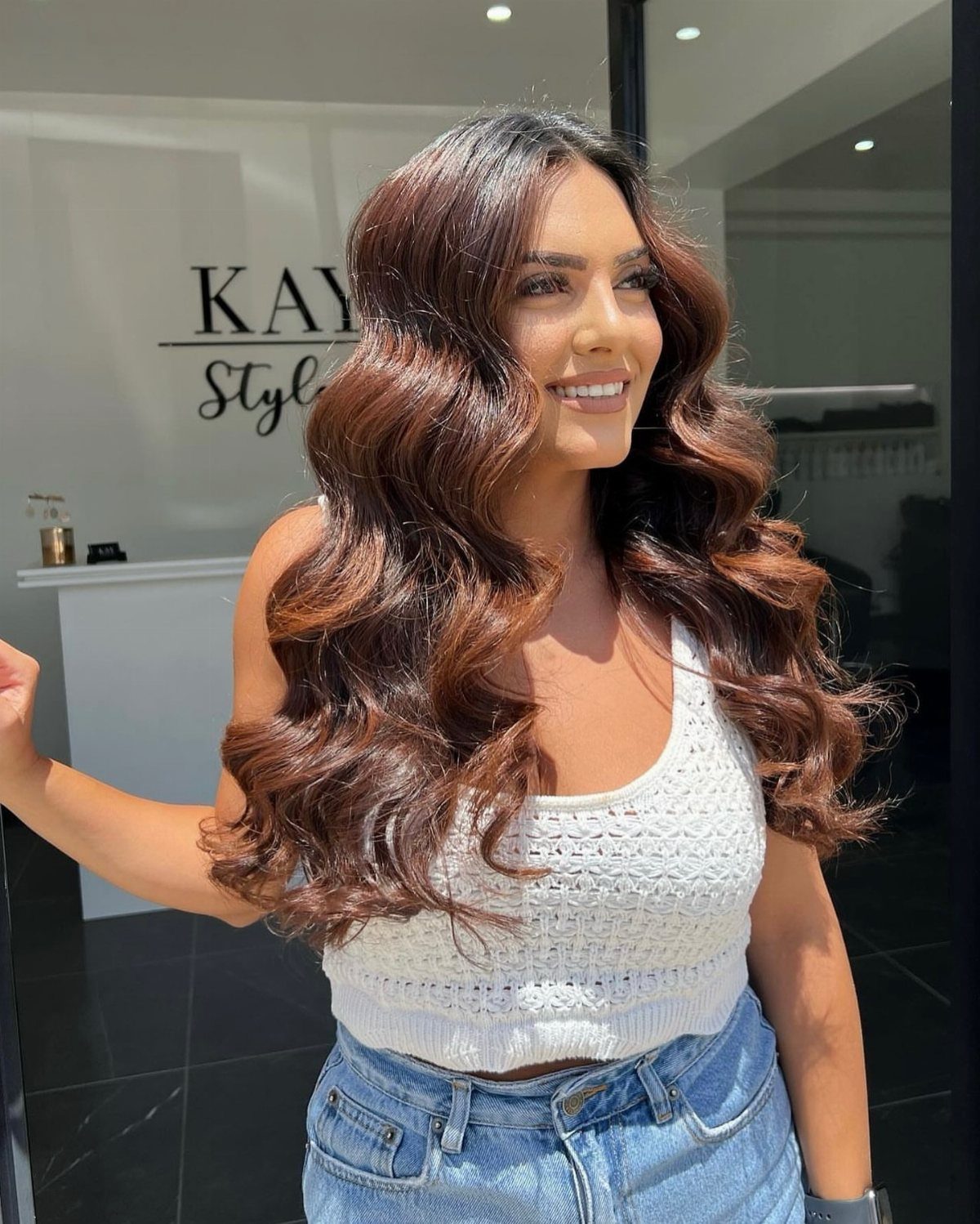 Woman displaying long brunette hair styled in glossy, sculptural curls