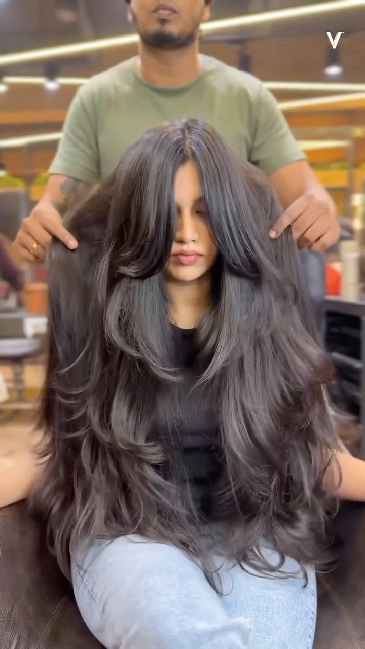 Long, dark waterfall layers cascade over a seated woman in a salon.