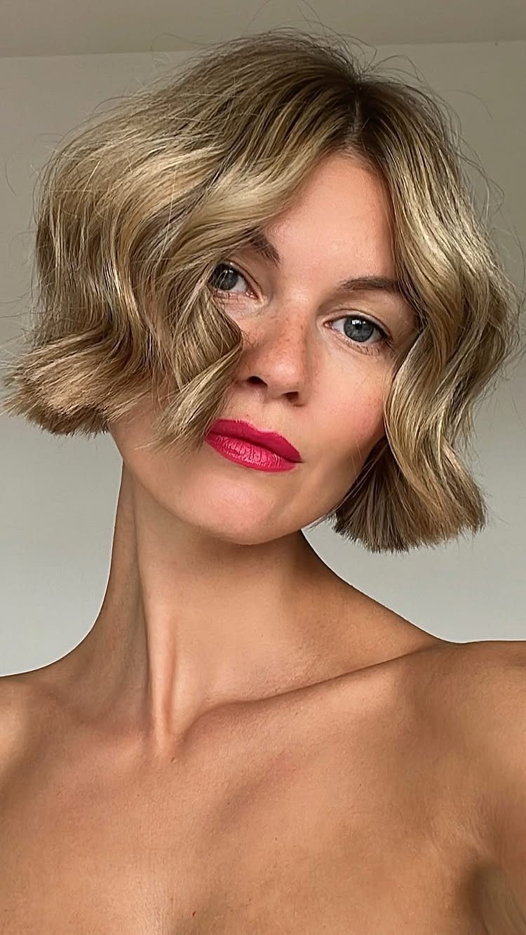 Woman with a tousled, wavy blonde bob and a deep side part