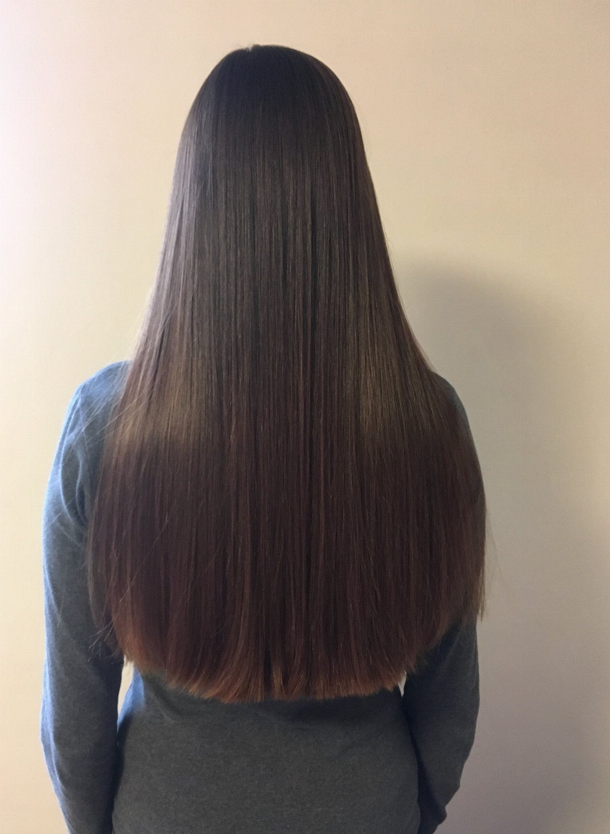 Long glossy dark hair falls straight down the back to a slightly uneven blunt hem