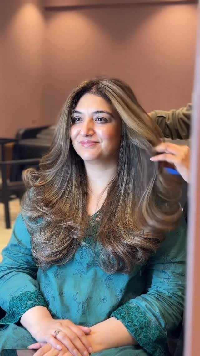 Woman with long dark brown hair, lighter highlights, and curled ends
