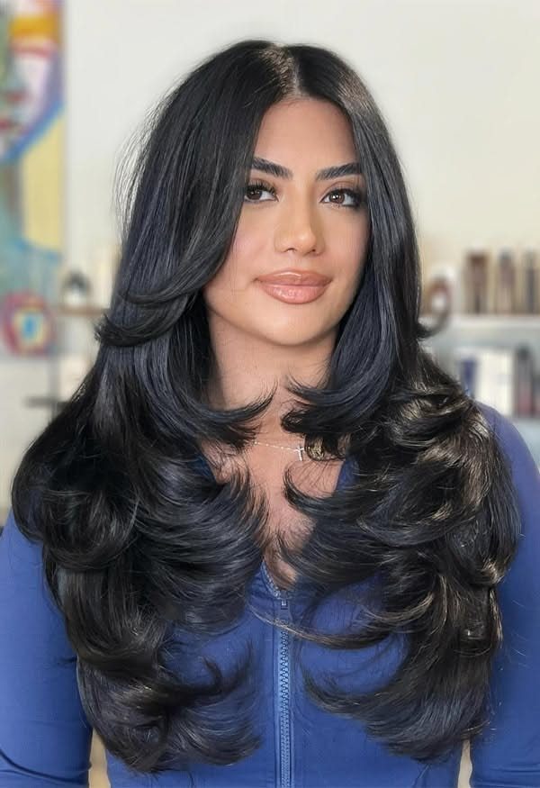 Woman with long black hair and face-framing layers curled softly at the ends
