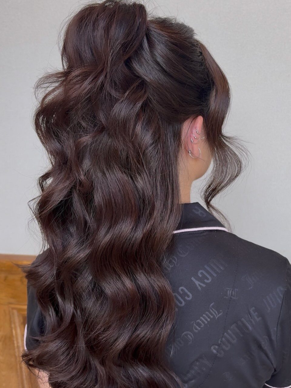 Long dark wavy hair styled half-up, viewed from behind