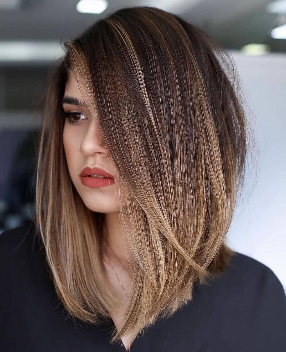 Woman wearing a sleek highlighted long bob with a deep side part