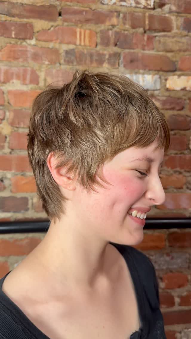 Short-haired person showing a layered pixie cut with sweeping fringe