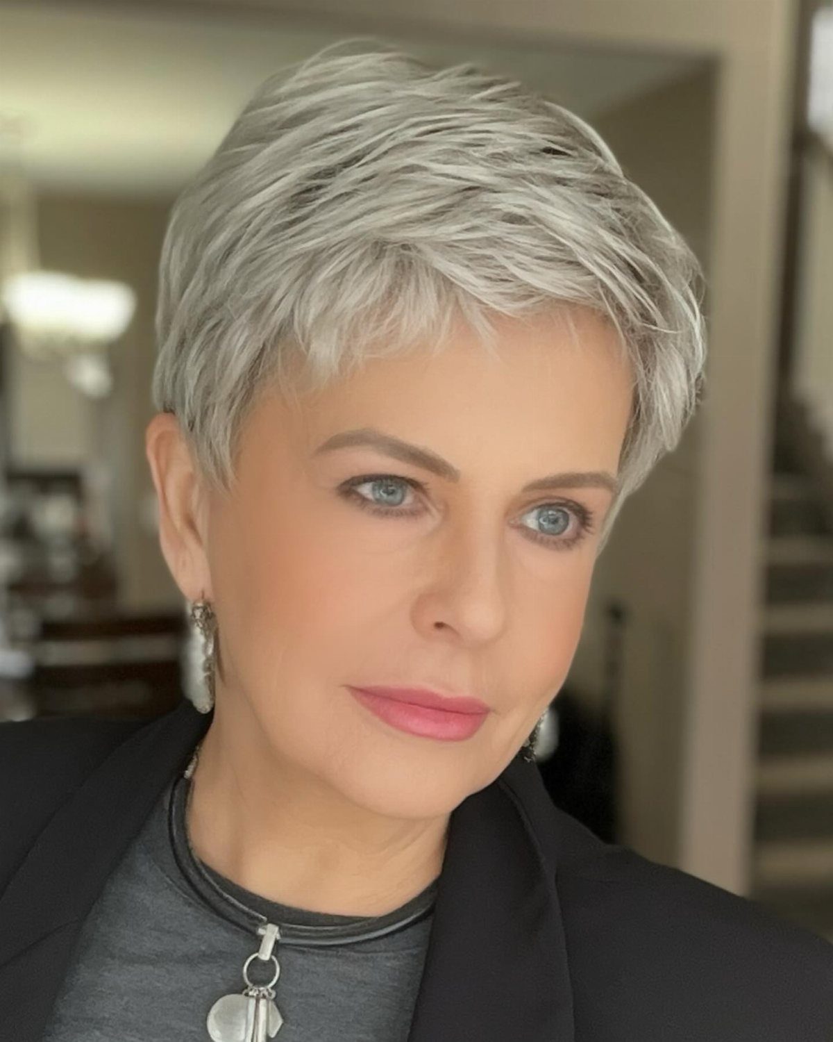 Woman showing a silver-blonde pixie with tapered sides and sweeping front layers