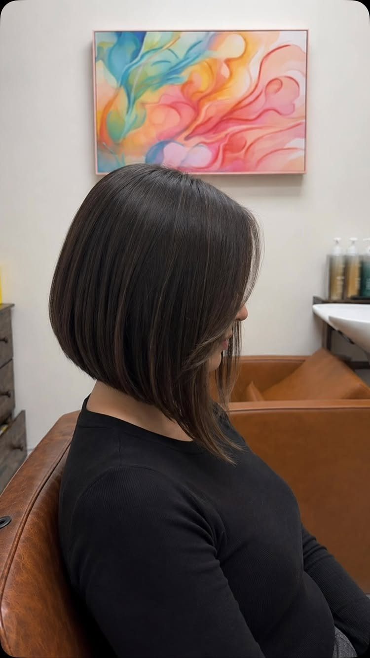 Glossy dark angled bob with a side-swept fringe, shorter at the back