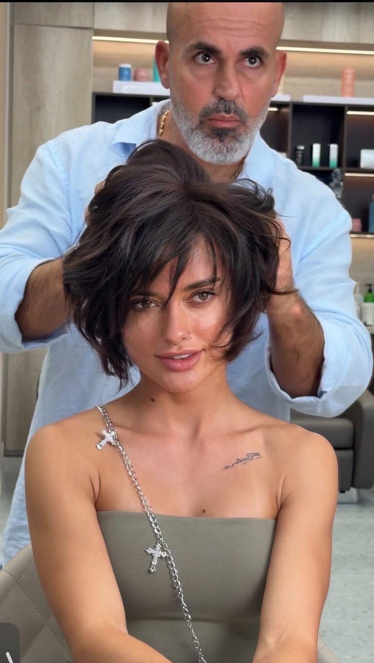 Woman showing a tousled dark bixie haircut with long side-swept bangs