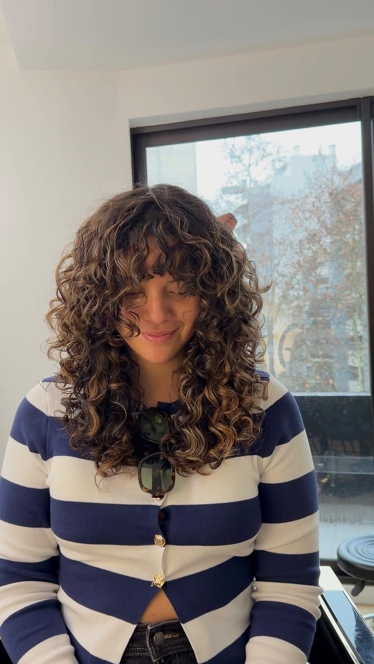Woman with a layered curly shag haircut and long natural brown curls