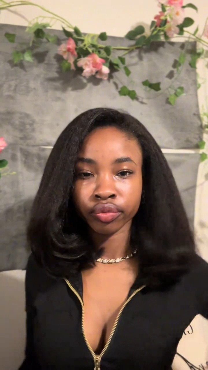Woman poses with a smooth, dark shoulder-length bob and a side part