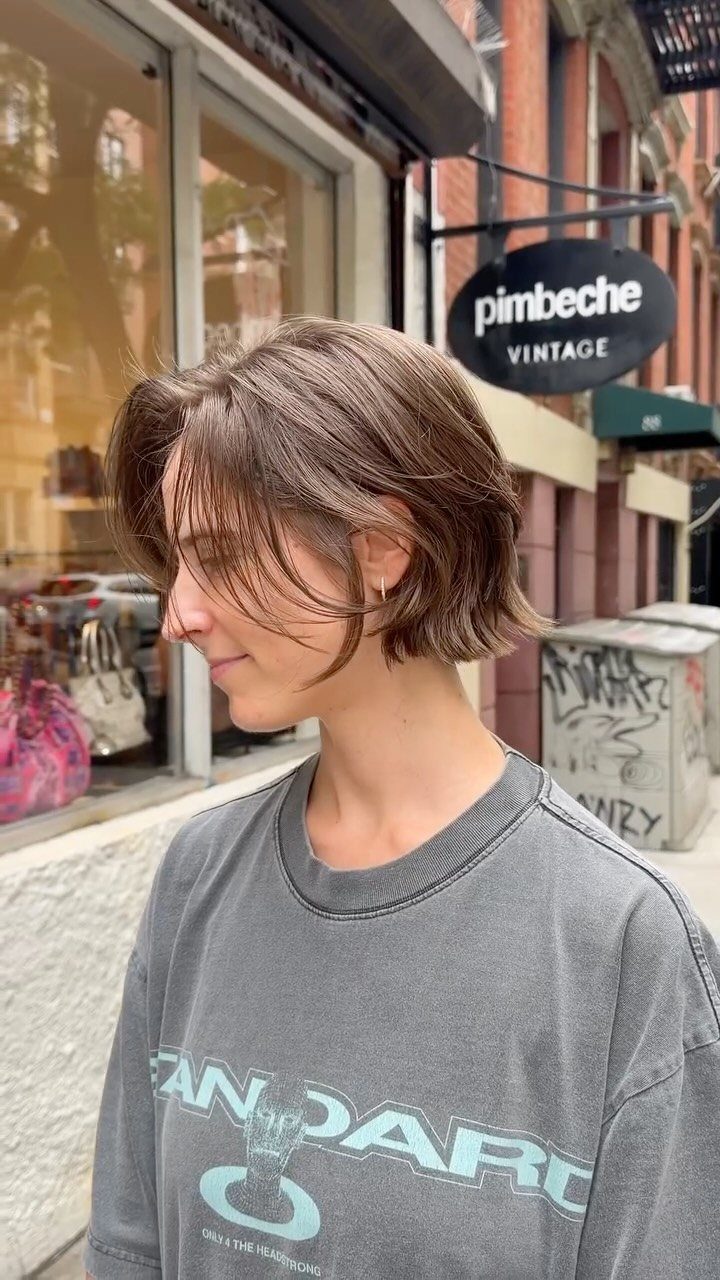 Short textured brown bob with wispy bangs photographed outside a shop