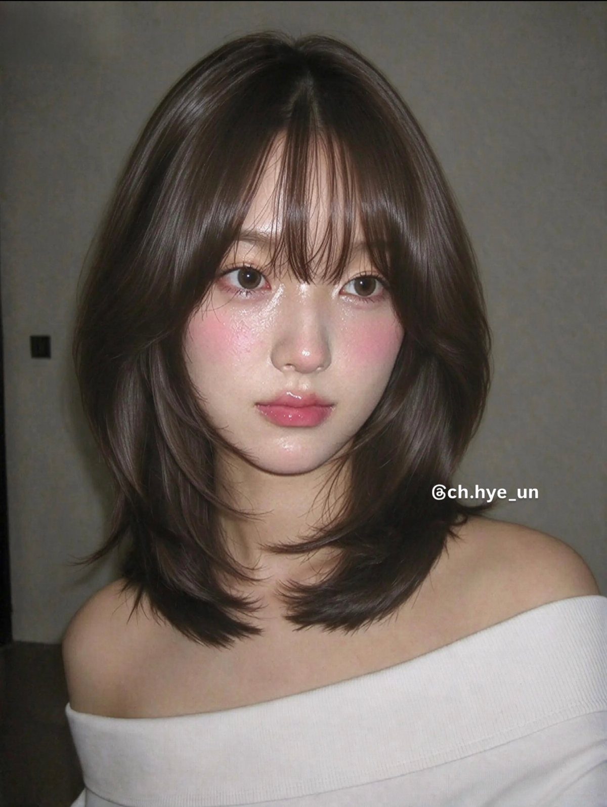 Woman with shoulder-length layered brown hair and long, parted curved bangs