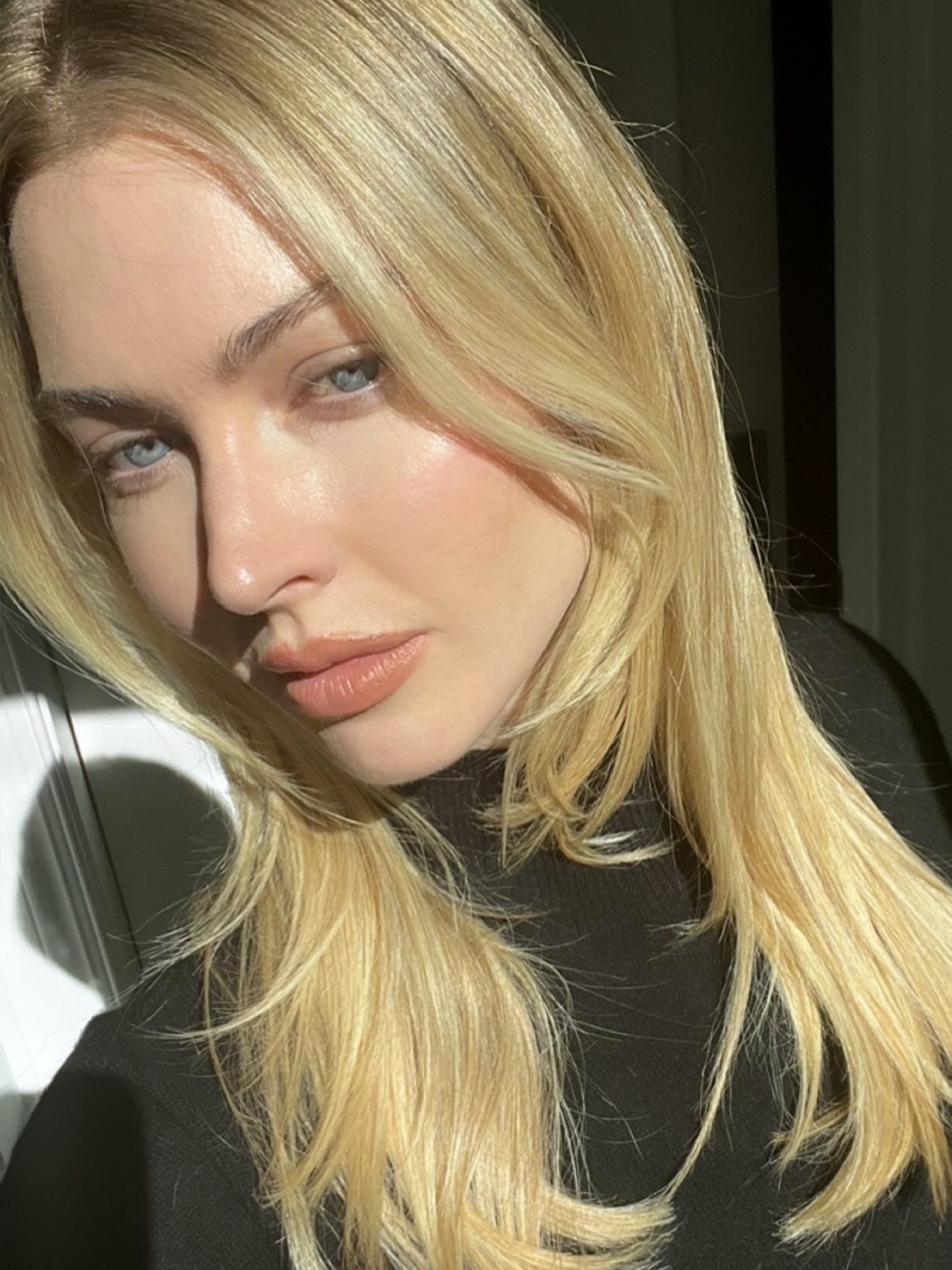 Woman with long straight blonde hair and center part in sunlight