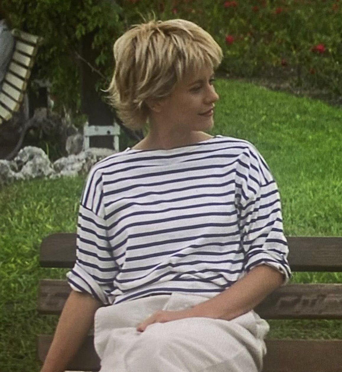 Woman sitting on a bench with short, tousled blonde layered hair